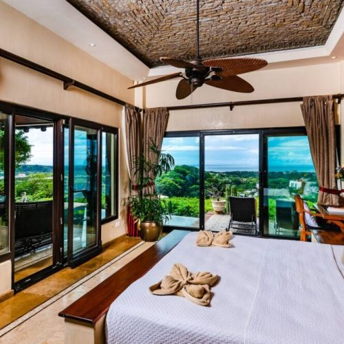 Relax in a comfortable bedroom while soaking in the scenic ocean and beach vistas, perfect for families or groups staying in Tamarindo.